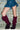 A person wearing a short denim skirt and AZALEA WANG IMOGINE PURPLE OMBRE FOLDED DETAIL STILETTO BOOTS stands in front of a wall made of glass blocks.