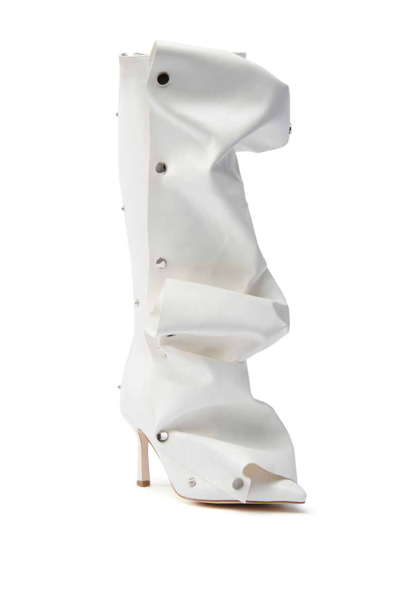 The AZALEA WANG IMOGINE WHITE BOOT features a knee-high, open-toe design with a crumpled faux leather texture and button-like accents. Its stiletto heel adds to the sculptural, avant-garde look.