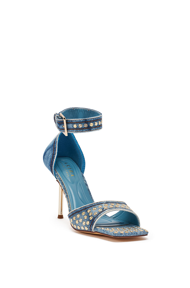 The AKIRA GOLD INANA DENIM STUD EMBELLISHED STILETTO SANDAL features blue denim, a metallic stiletto heel, ankle strap, open toe, and silver stud details. A matching blue insole completes this polished and stylish high heel sandal. 4