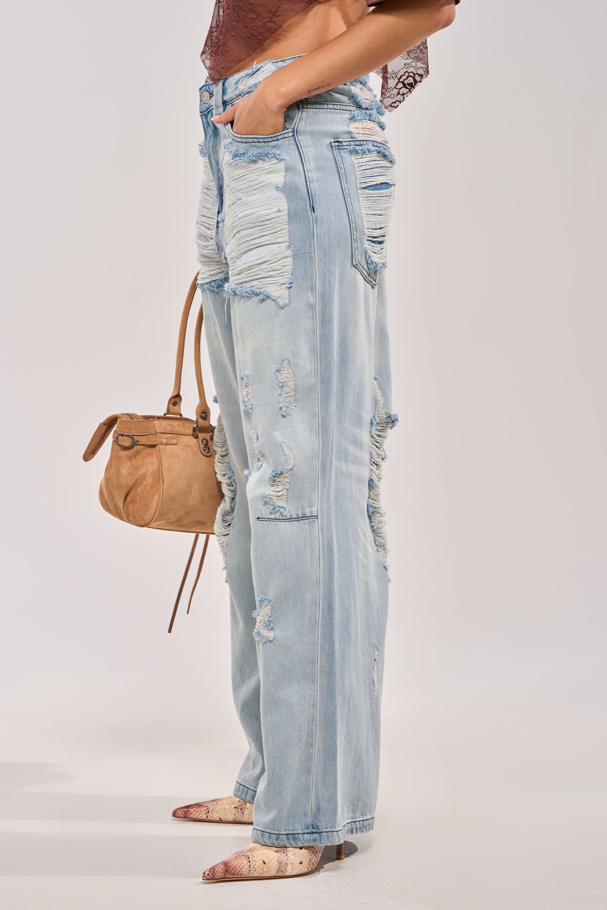 A person in SUPER DISTRESSED WIDE LEG DENIM (light blue), a brown lace top, snake print pointed-toe shoes, and holding a tan handbag is shown from waist to feet against a light background. 2
