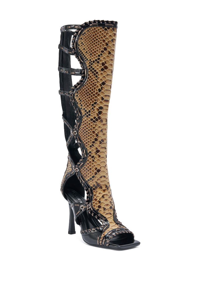 The AKIRA GOLD INDRANI BLACK HIGH SHAFT GLADIATOR SANDAL features knee-high stiletto heels, brown snakeskin pattern, black faux patent leather accents, cutout sides, and lace-up details for a modern, edgy gladiator look. 9