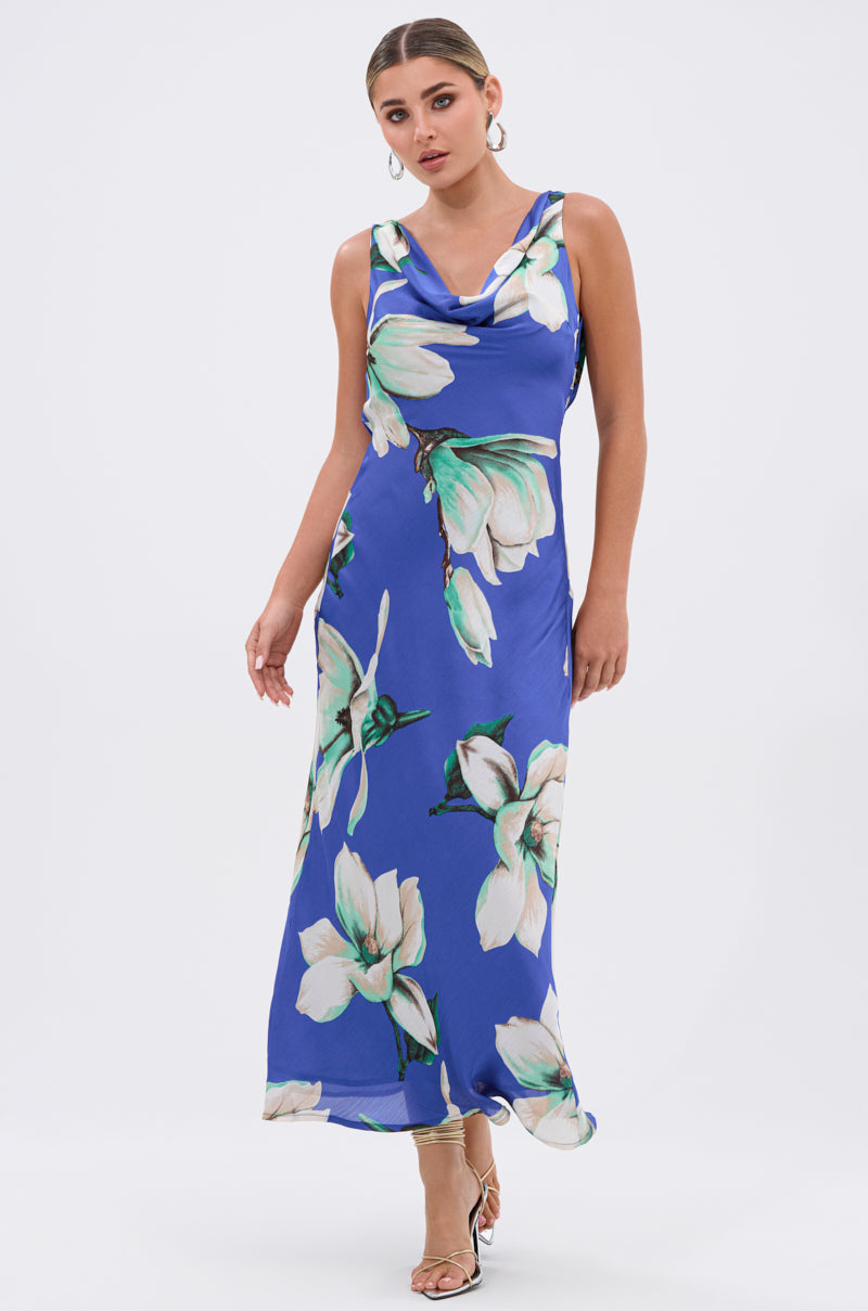 The SOMETHING SWEET FLORAL MAXI DRESS features a sleeveless blue design with bold white floral prints—ideal as a chic choice for summer weddings.