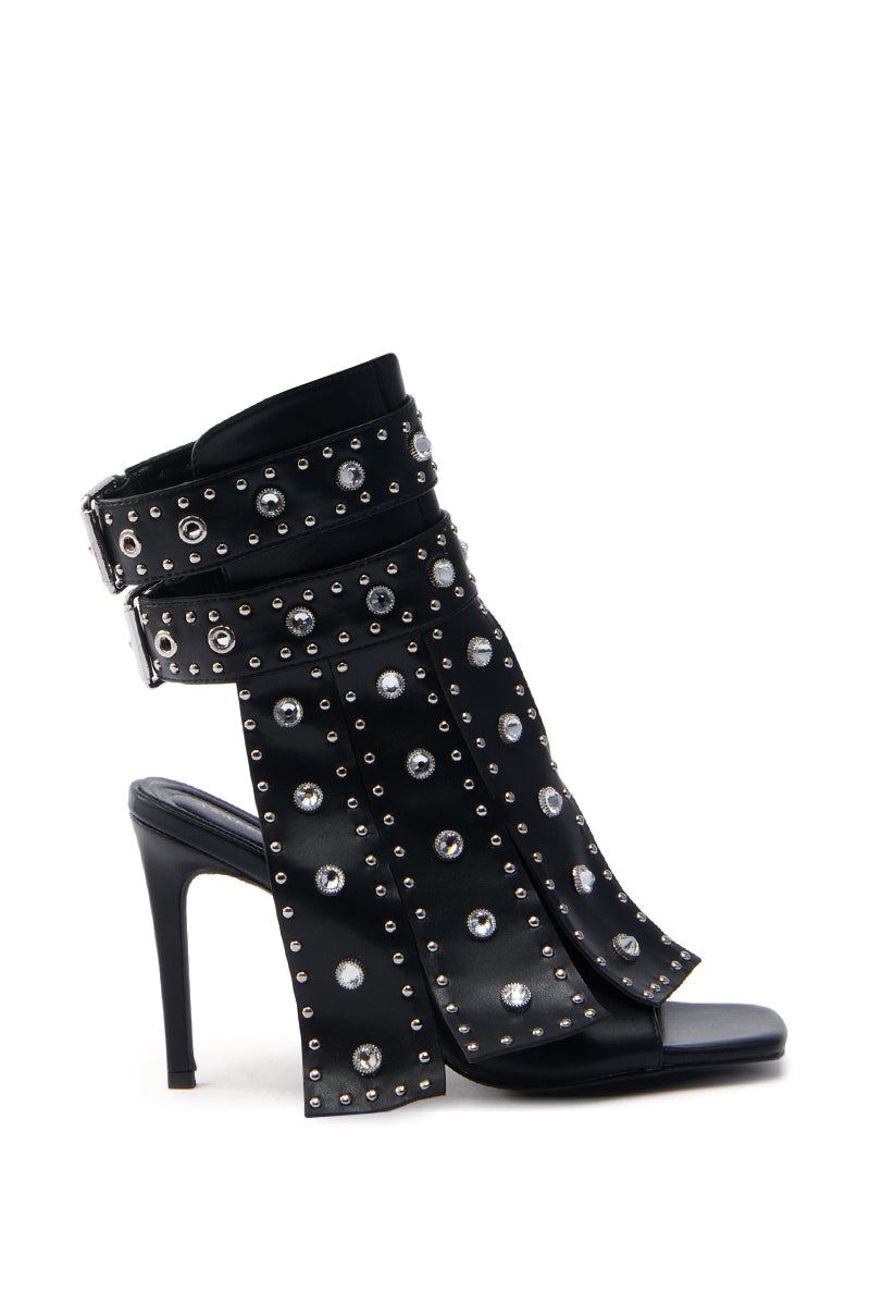 The AZALEA WANG IRELYN BLACK EMBELLISHED SANDAL is a bold high-heeled sandal with an open toe, crafted from faux leather. It features wide straps adorned with silver studs, a stiletto heel, and an ankle buckle closure.
