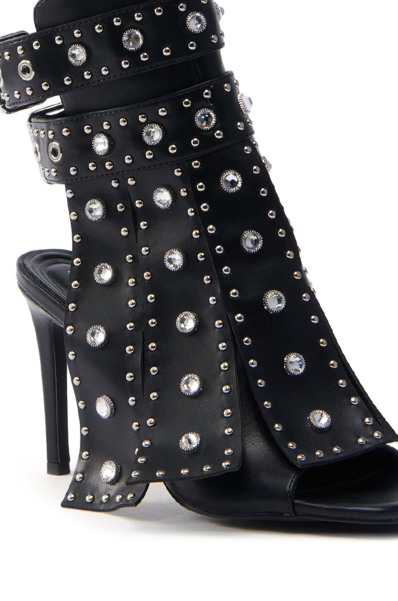 The AZALEA WANG IRELYN BLACK EMBELLISHED SANDAL is a faux leather standout featuring a stiletto heel, open toe, and silver studded circular accents. Unique layered strap details enhance its bold, edgy appearance.