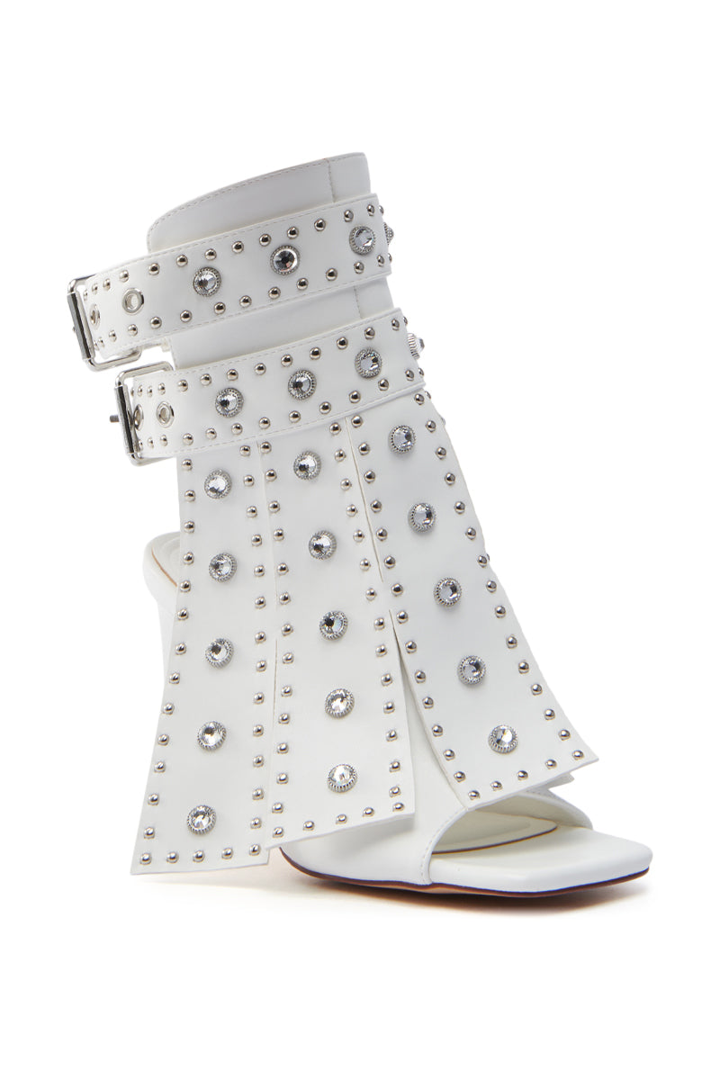 The AZALEA WANG IRELYN WHITE EMBELLISHED SANDAL is a faux leather, open-toe stiletto with calf-high cuff adorned with silver studs and rhinestones, featuring two adjustable buckles and a sculpted heel.