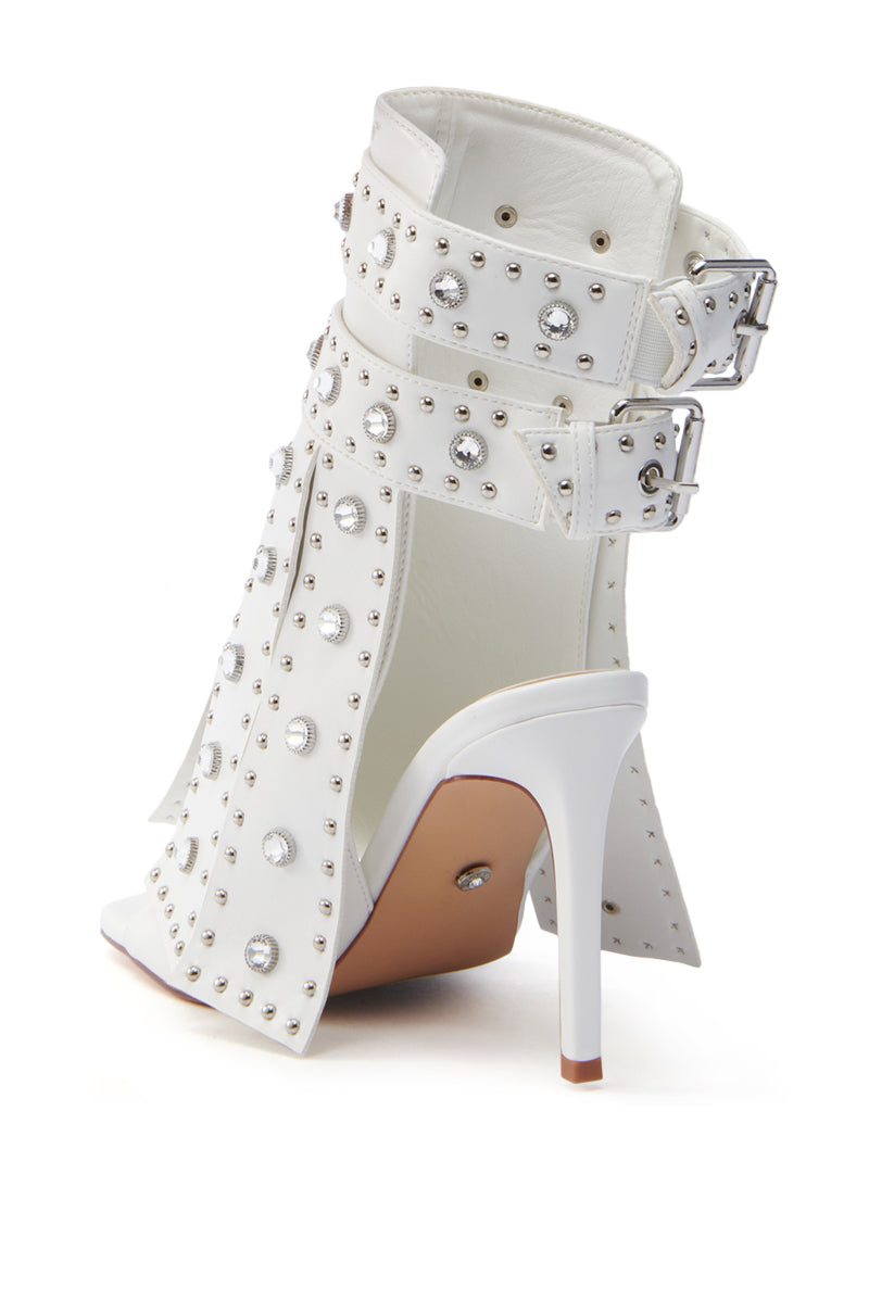 The AZALEA WANG IRELYN WHITE EMBELLISHED SANDAL features a sleek open-back design, stiletto heel, and adjustable ankle straps with metal buckles. It's adorned with silver studs and rhinestones, offering a stylish alternative to classic studded booties.