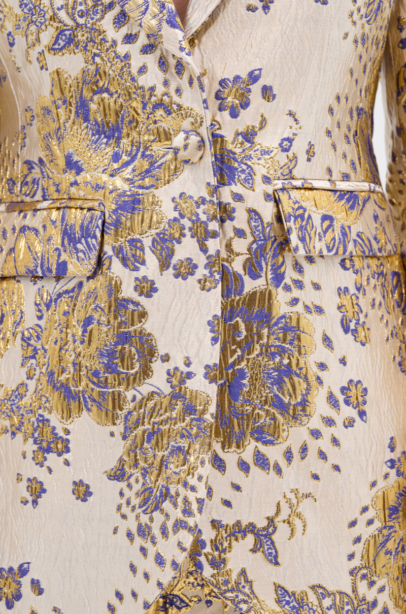 Close-up of the GOLDIE BROCADE BLAZER, a cream suit jacket with metallic gold and blue floral brocade, two front pockets, and a single button closure that enhances its textured, elegant look.