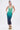 A woman poses against a plain background in the UNDER THE SEA RHINESTONE OMBRE MIDI DRESS, featuring a sleeveless halter neck and a gradient from green to dark blue, styled with sparkling floral high-heeled sandals.