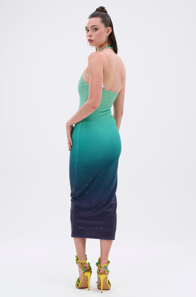 A woman with dark hair in a high ponytail models the UNDER THE SEA RHINESTONE OMBRE MIDI DRESS and yellow embellished high-heeled sandals, standing against a plain white background.