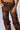 A person is shown from the waist down wearing the OUT LIKE A BANDIT FAUX LEATHER CARGO PANT IN BROWN, featuring a high-rise baggy silhouette with multiple pockets and zippers. One hand rests near the waistband, while the other is partially visible near a pocket. The pants have a rugged, distressed finish in brown tie-dye leather.