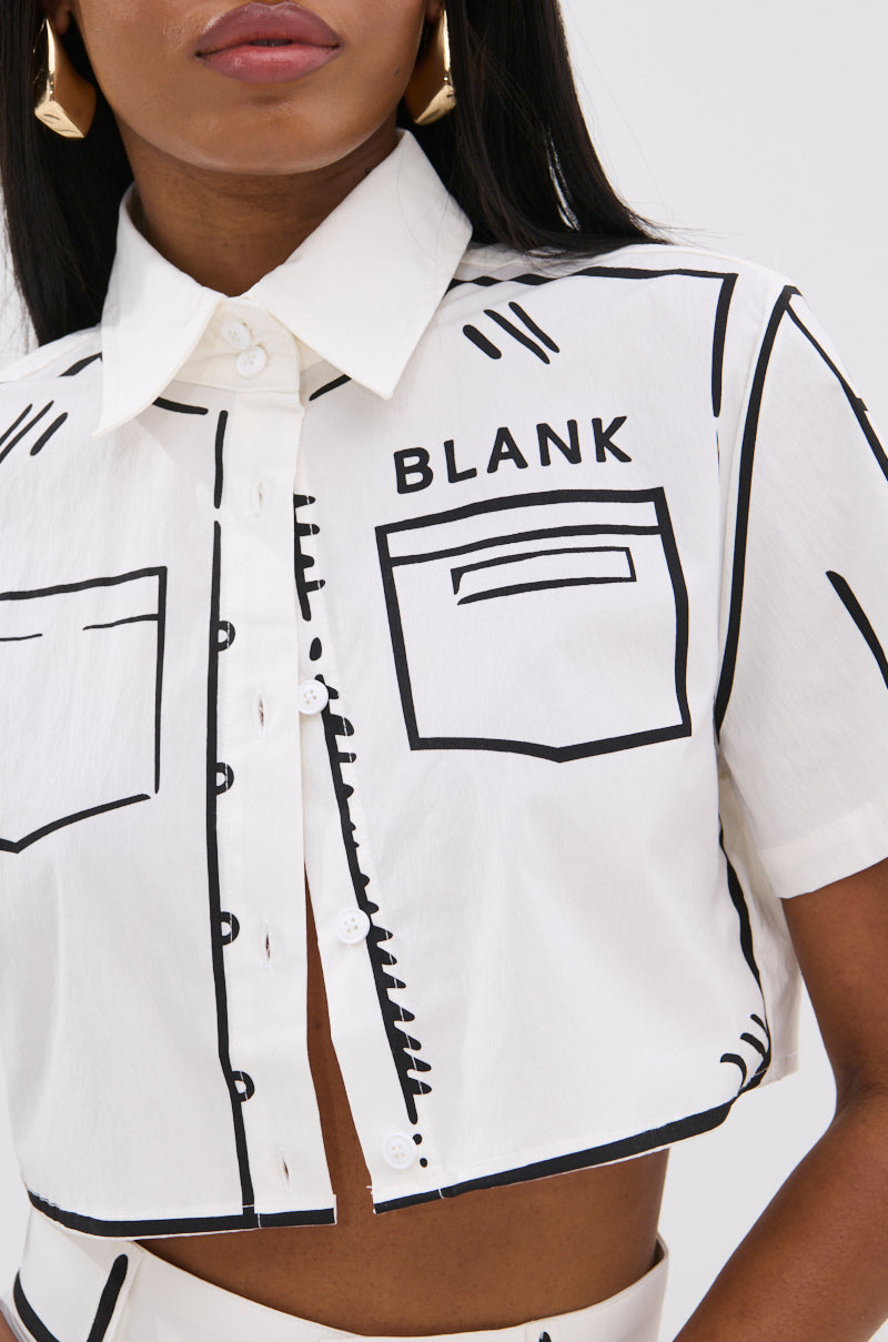 A woman wears the BLANK SPACE Cropped Short Sleeve Button Down, a white shirt with black pop-art outlines and "BLANK" above a front pocket graphic. She has long dark hair and geometric earrings.