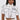 A woman wears the BLANK SPACE CROPPED SHORT SLEEVE BUTTON DOWN, a pop-art inspired white shirt with black outlines and "BLANK" on the pocket, paired with matching high-waisted pants, standing against a plain light background.