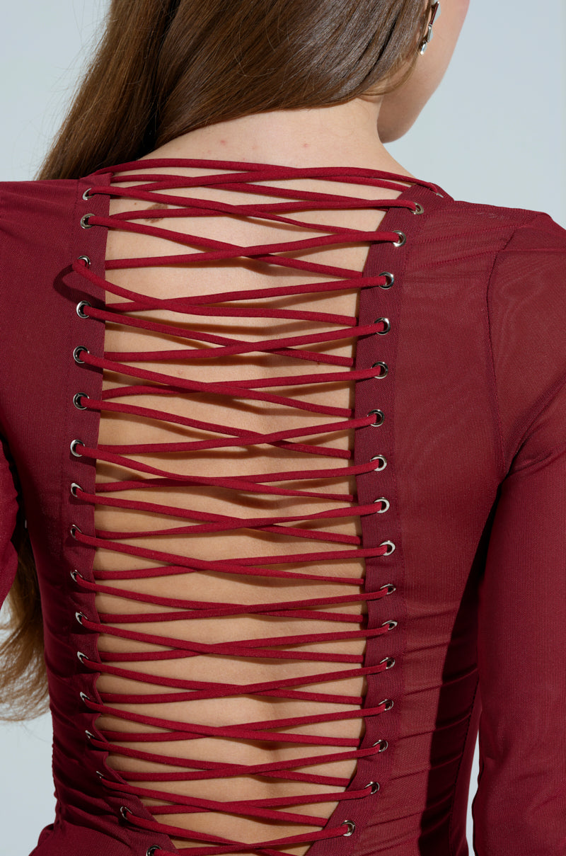 The image features a person with long brown hair in the PRIME ENERGY MESH MAXI DRESS, showcasing an elegant lace-up back design with metal eyelets revealing skin beneath, adding mystery and elegance similar to a scoop neckline.