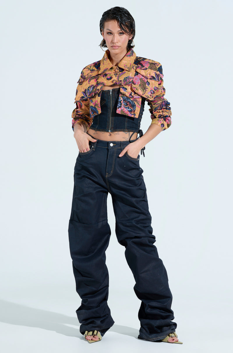 Dressed in an ULTRA CROP CARGO BOMBER over a black top, with loose black pants and sandals, a person with short hair exudes effortless style against a plain, light background, hands casually tucked in pockets.
