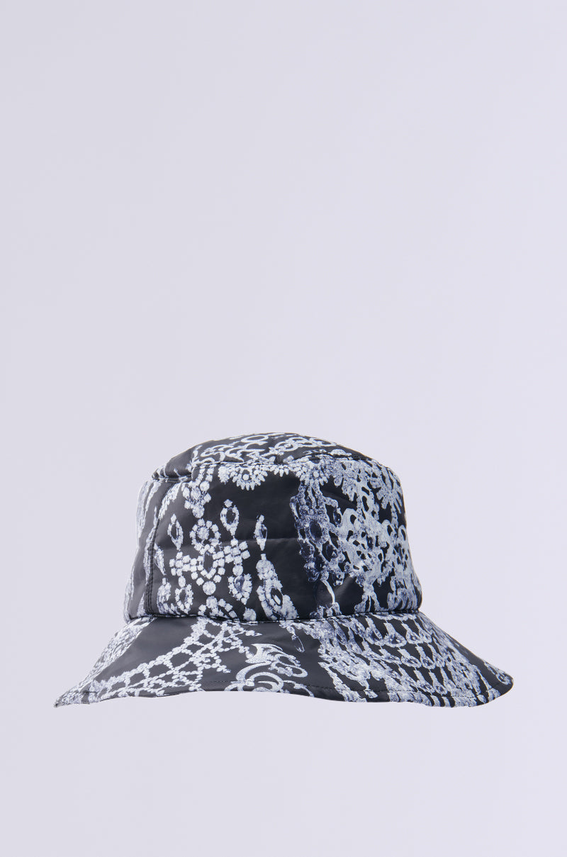 The UNDER THE LIGHTS PUFFER BUCKET HAT showcases a black base with an intricate white lace pattern, enhanced by a plain light gray background for added sophistication to its insulated design. 2