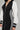 A person donning a chic DO YOU MIND MAXI DRESS, complemented by a stylish black jacket featuring a color-block design with white sleeves and side stripes. The jacket is equipped with a front zipper and sporty cuffs, capturing the essence of sporty chic flawlessly. A silver chain necklace adorns their neck for an added touch of elegance.