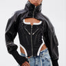 A woman poses confidently in the NOW YOU SEE ME BOLERO, styled over a structured black-and-white corset top and high-waisted, distressed blue jeans. With slicked-back hair and a neutral expression, she showcases perfect transitional outerwear style.
