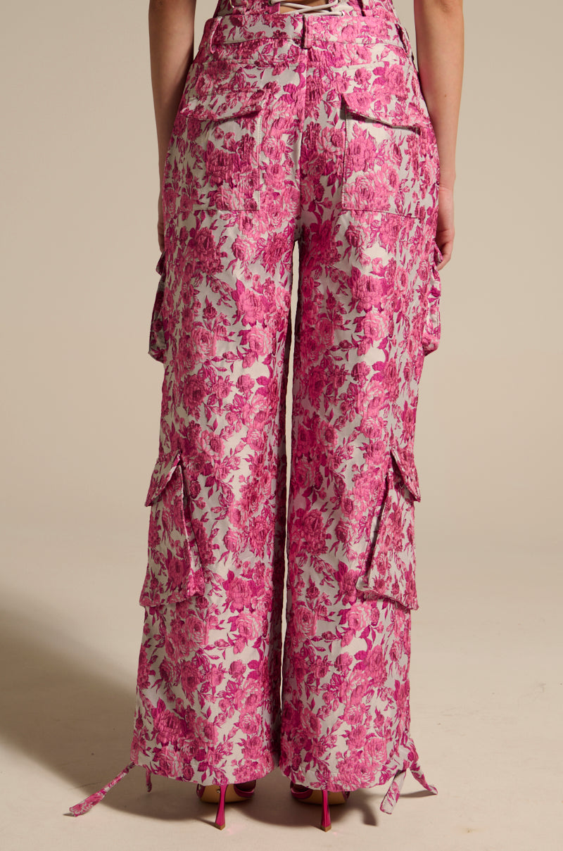 Facing forward, an individual models the Miley Jacquard Cargo Pants, featuring high-rise wide-leg design and pink floral patterns in jacquard fabric. Complete with multiple pockets and ties, these pants are ideally paired with pink heels. 5
