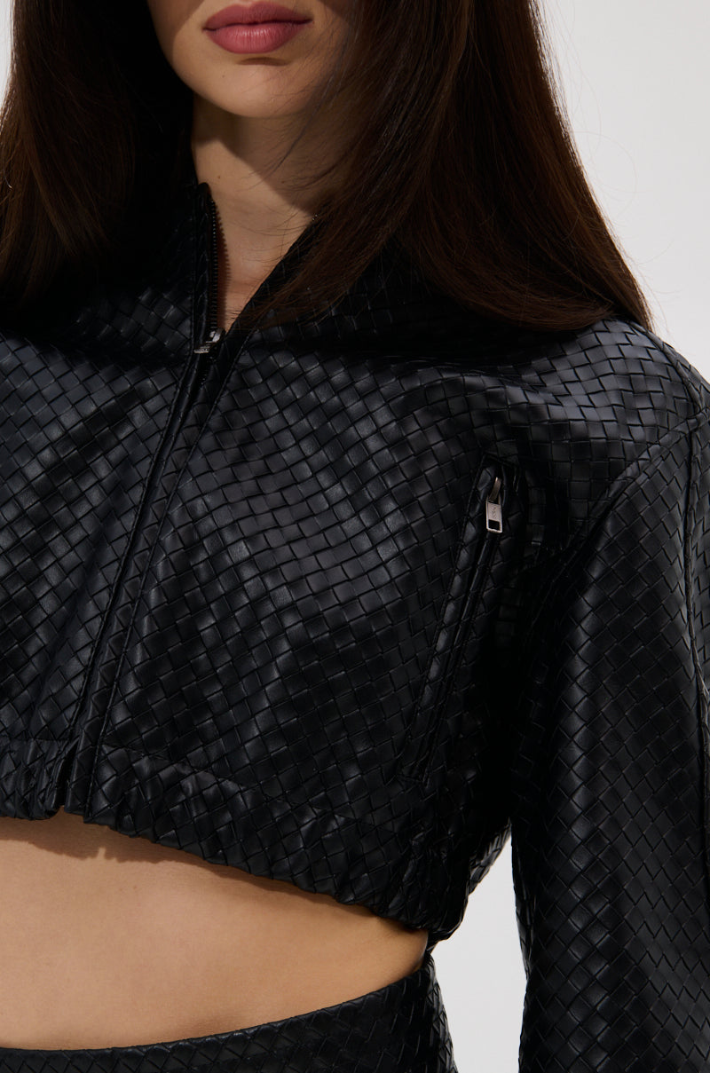 A woman wears the KYLIE HOODED BOMBER, a black, woven-texture, cropped jacket with a zipper. Only her lower face, upper body, and part of her long brown hair are visible. 11