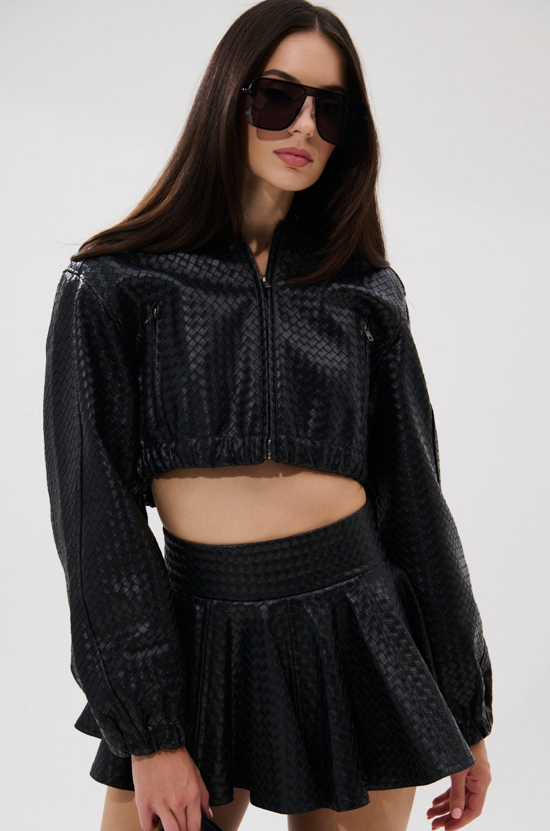 A woman with long brown hair wears large sunglasses and the KYLIE HOODED BOMBER, styled with a matching high-waisted mini skirt. She poses against a plain light background. 2