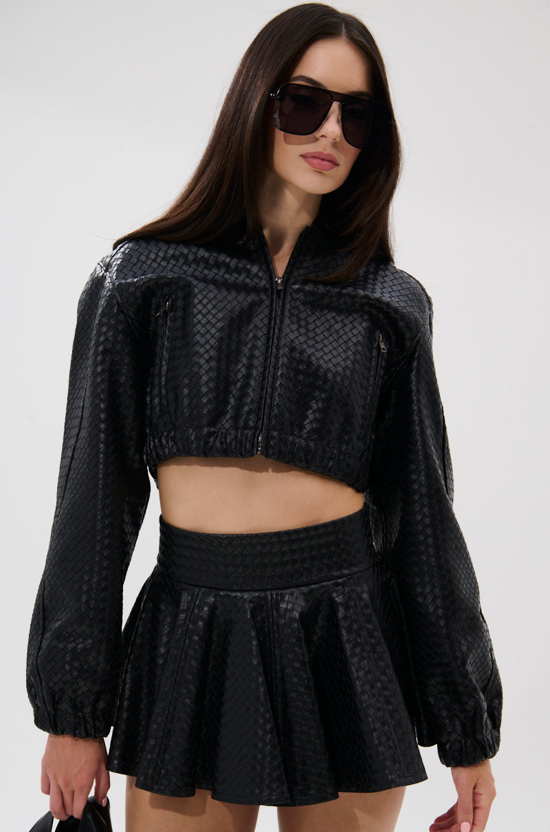 A woman wearing the KYLIE HOODED BOMBER, oversized sunglasses, and a matching high-waisted flared mini skirt stands against a plain light background. 4
