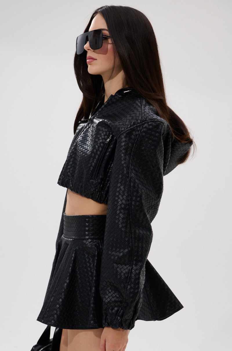 A woman with long dark hair wears the KYLIE HOODED BOMBER, oversized sunglasses, and a matching high-waisted skirt, standing against a plain white background. 6