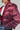 A person wearing the FAYE RHINESTONE PUFFER in burgundy, featuring sparkling sequins and a hood. The jacket is styled with a white shirt and distressed denim against a light gray background.