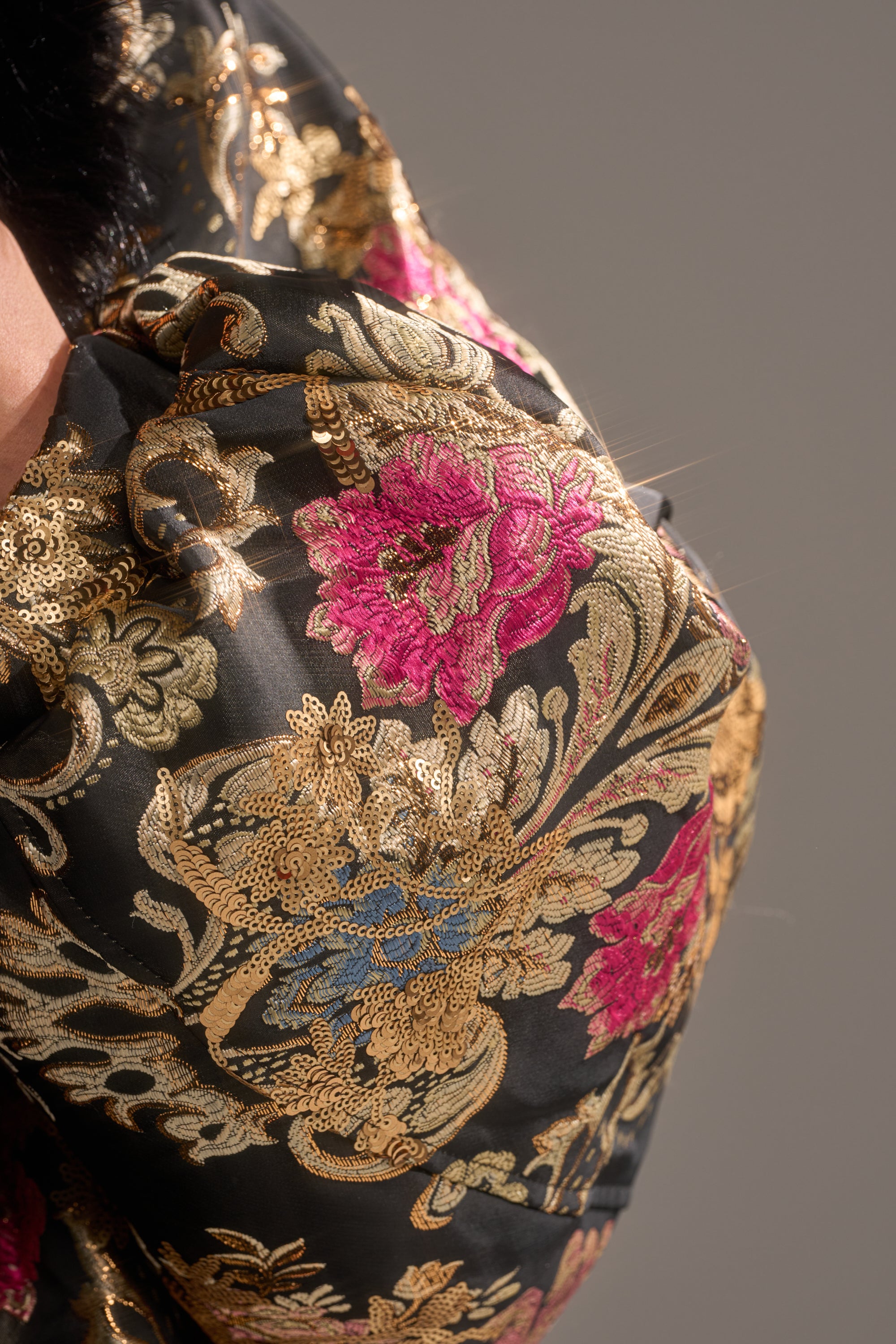 Close-up of the LOLA COCOON COAT IN BROCADE, featuring luxurious black brocade fabric adorned with intricate gold, pink, and blue floral embroidery for a refined, elegant look.