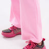 Someone wearing light pink pants and AZALEA WANG ISABEAU FUCHSIA COLOR BLOCKED EMBELLISHED SNEAKERS stands on a white surface.