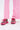 A person wearing loose pink pants and the AZALEA WANG ISABEAU FUCHSIA COLOR BLOCKED EMBELLISHED SNEAKER stands on a white background.