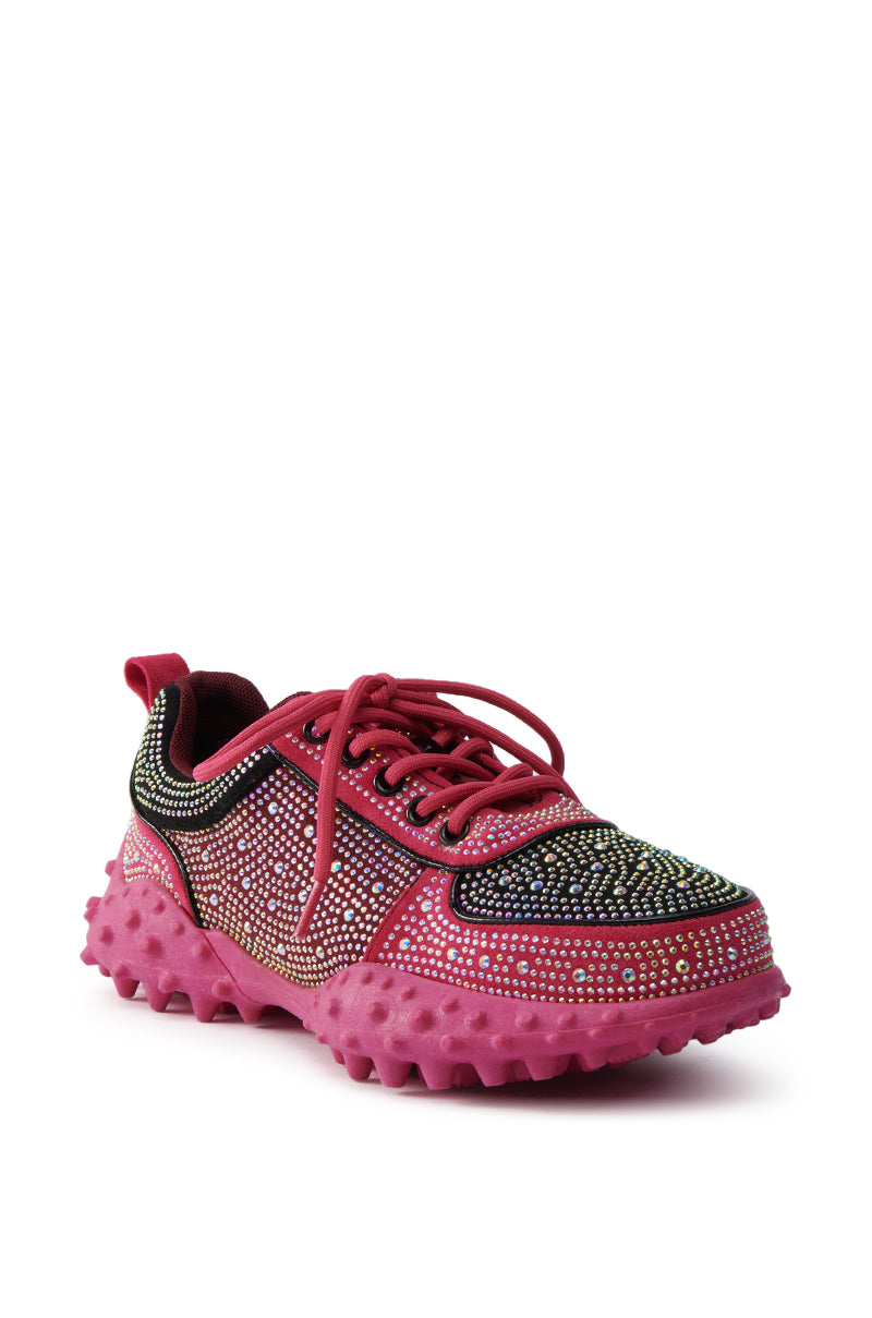 The AZALEA WANG ISABEAU FUCHSIA COLOR BLOCKED EMBELLISHED SNEAKER features a black and pink upper, pink laces and sole, chunky cleated rubber base, and is adorned with small multicolored rhinestones for extra sparkle.