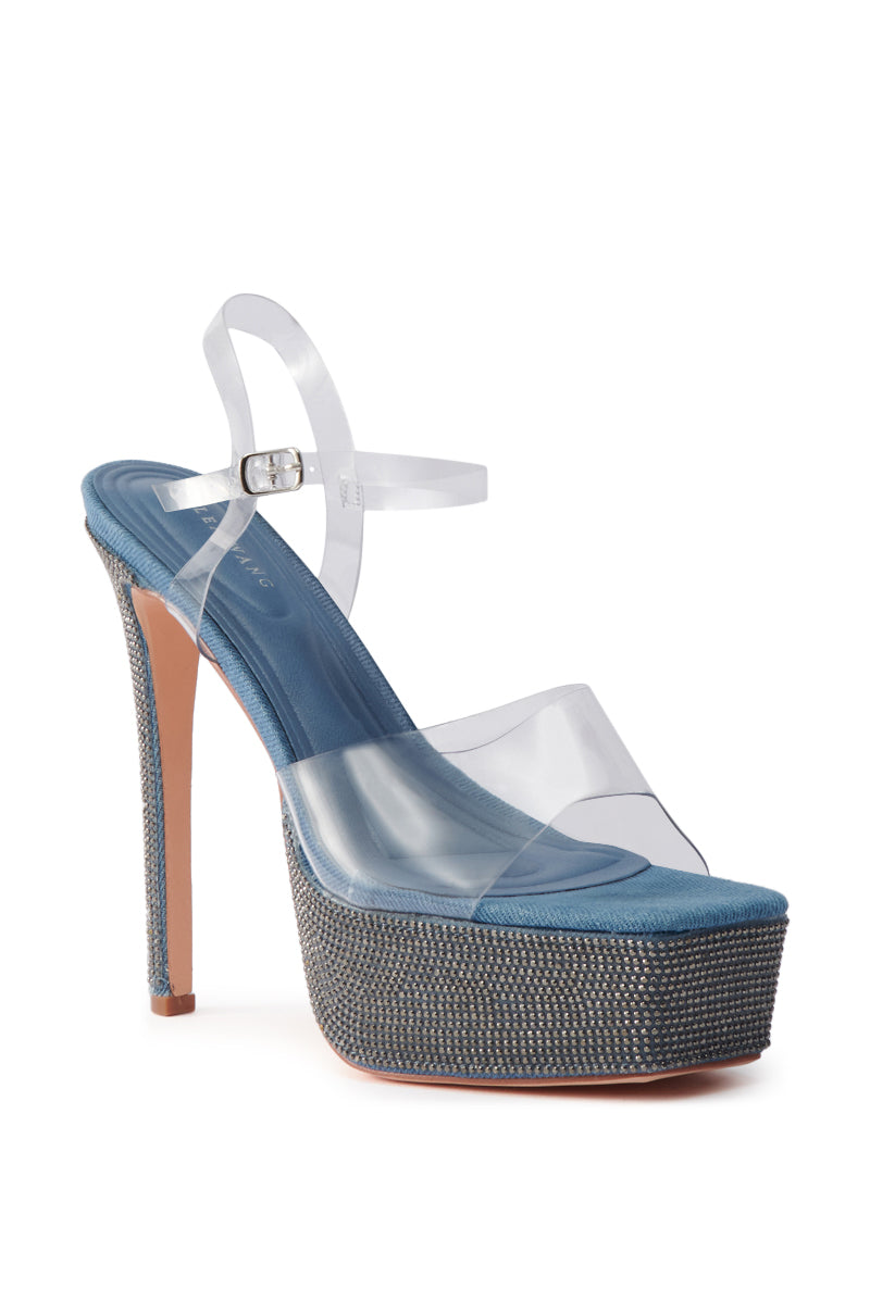 The AZALEA WANG ISAURA DENIM PLATFORM RHINESTONE SANDAL features high heels, a sparkling rhinestone-embellished denim platform and heel, clear PVC ankle and toe straps, plus a blue insole.