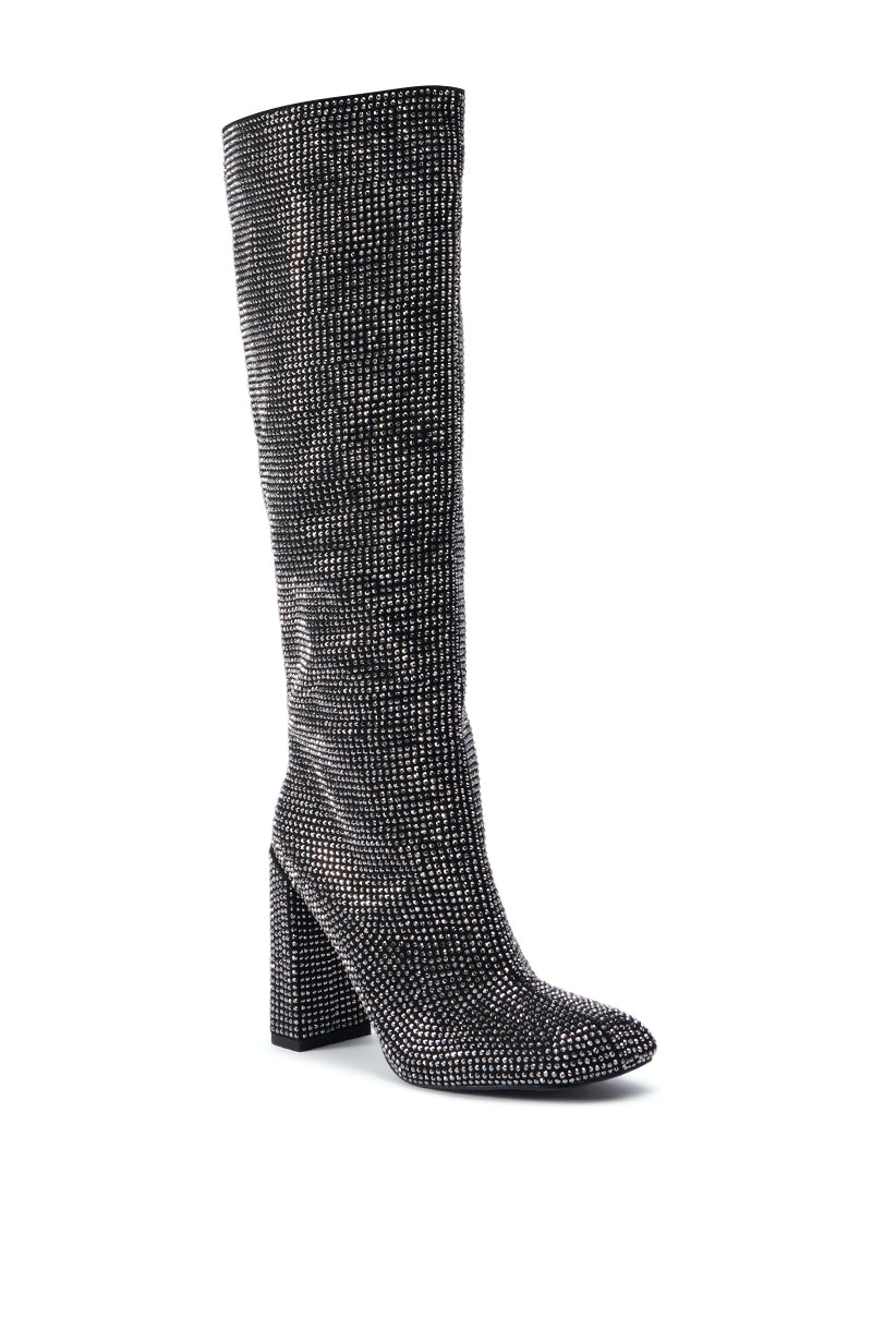 The AZALEA WANG ISKANDER BLACK RHINESTONE BOOT is a knee-high boot with a chunky high heel, adorned with numerous small sparkling stones that create a shimmering effect. Its densely packed, glittering surface gives the black rhinestone boot a luxurious and glamorous appearance. 3