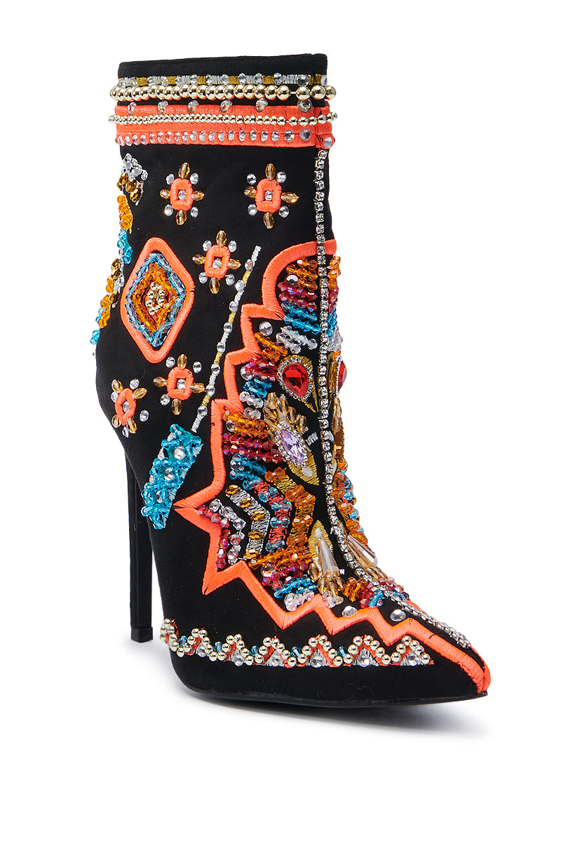 Introducing the AZALEA WANG ITSY BITSY MULTI EMBELLISHED BOOTIE: a high-heeled faux suede masterpiece, richly adorned with colorful beads and sequins forming intricate patterns. The bootie features vibrant orange, blue, and gold motifs that create an ornate and lively look. It boasts a pointed toe coupled with a sleek stiletto heel for added elegance.