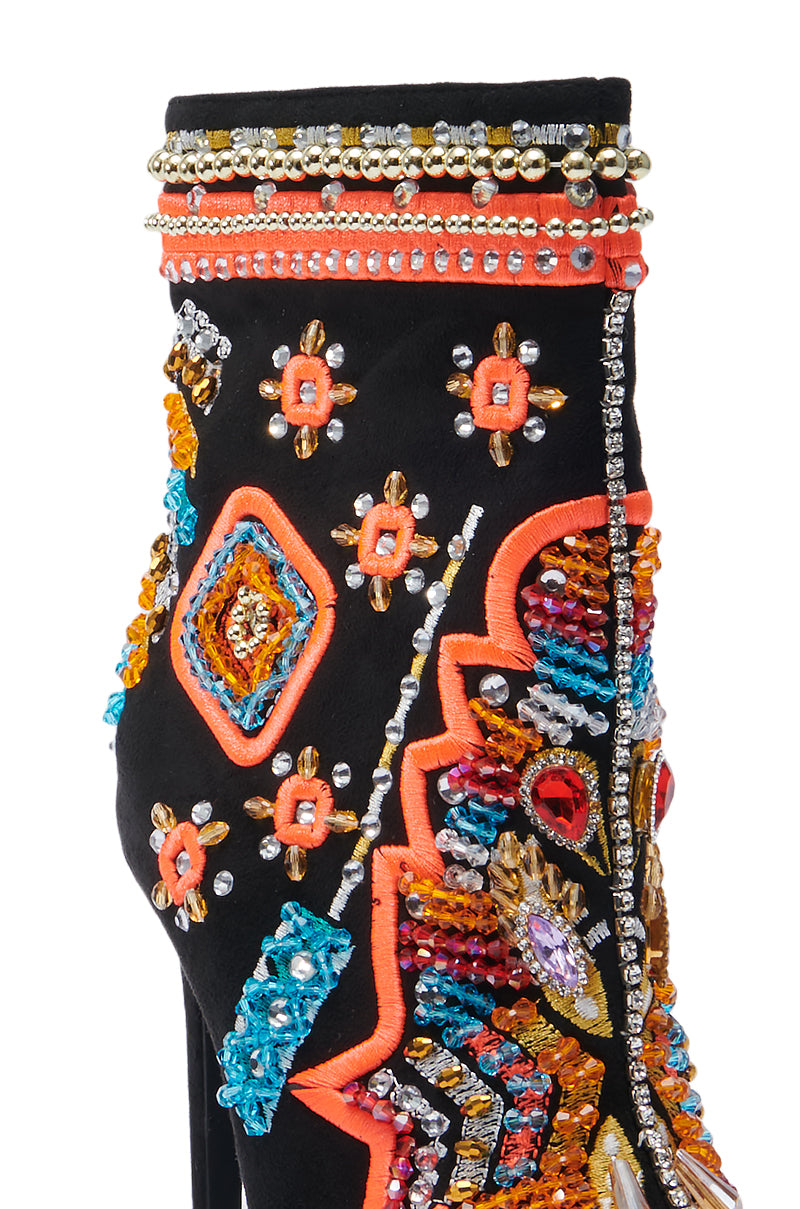 Close-up of the AZALEA WANG ITSY BITSY MULTI EMBELLISHED BOOTIE, showcasing its colorful and intricately beaded and embroidered design. It features geometric patterns in vibrant shades of orange, blue, and gold, adorned with rhinestones and small beads on a black fabric background.