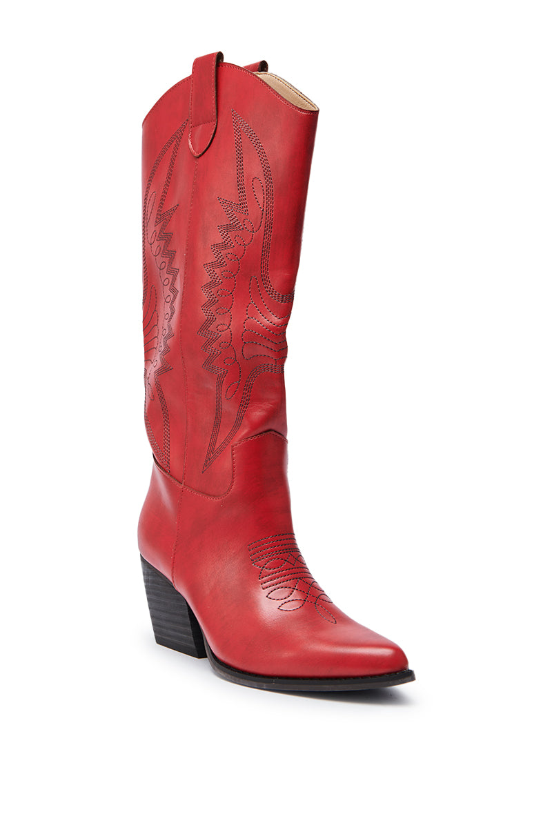 The IZABELLA WATERMELON WESTERN BOOT is a tall red faux leather cowboy boot with black decorative stitching, pointed toe, and chunky angled heel, shown knee-high against a white background.
