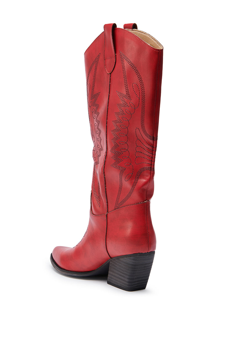 The IZABELLA WATERMELON WESTERN BOOT is a tall red knee-high cowboy boot in faux leather, featuring decorative stitching, pointed toe, pull straps, and a stacked block heel, shown from a rear side angle on a white background.