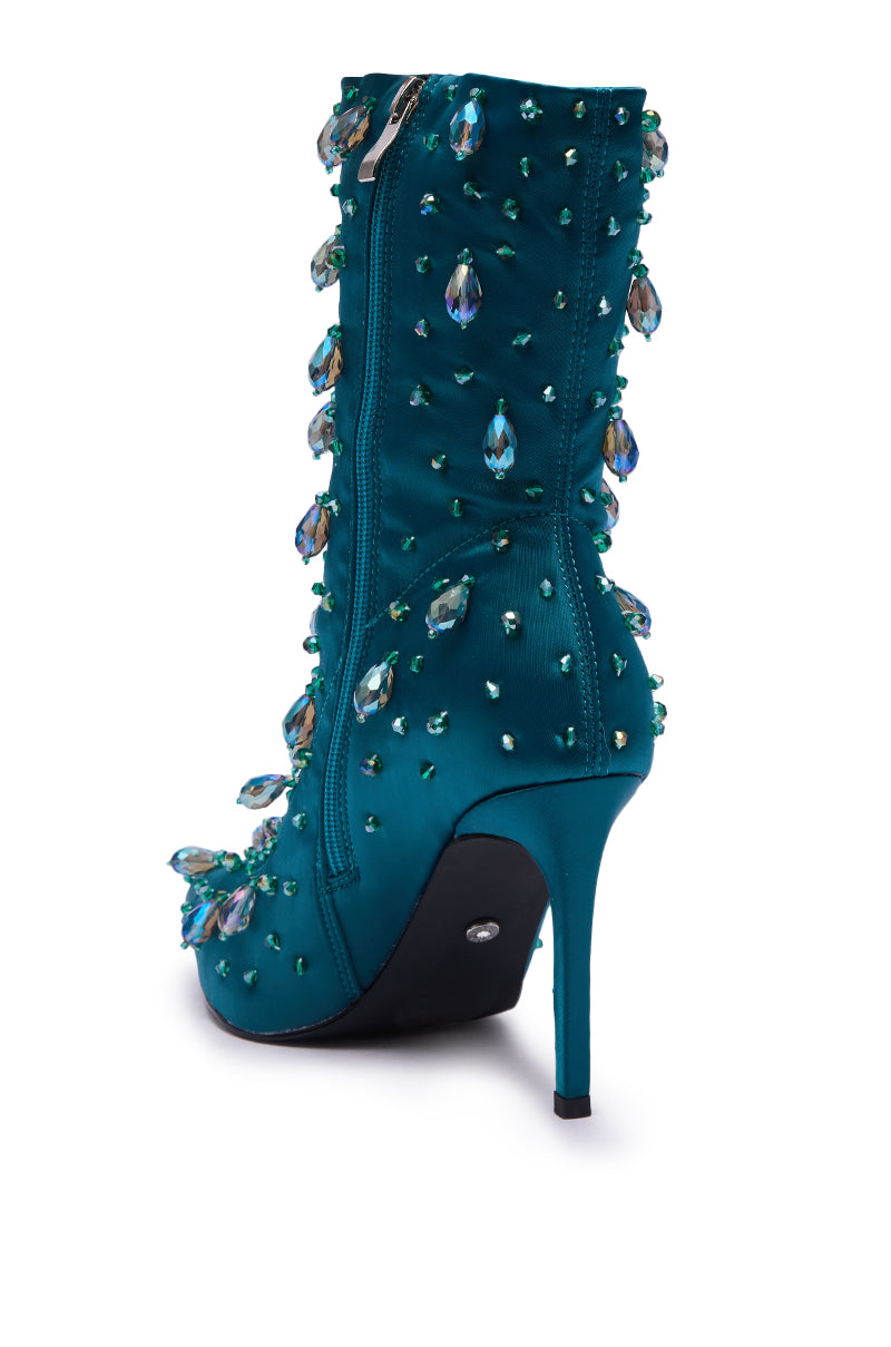 The AZALEA WANG IZIDOR TEAL EMBELLISHED RHINESTONE BOOTIE, featuring a stiletto heel and teardrop-shaped crystal embellishments, is shown from a back side angle on a white background.