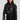 Dressed in the WHY SO SERIOUS METAL TRIM MOTO jacket, a woman exudes biker-chic style with its shiny black faux leather and metallic hardware detailing. She effortlessly pairs it with a black zippered dress, her long hair flowing and sunglasses on, while carrying a matching black handbag against the plain white backdrop.