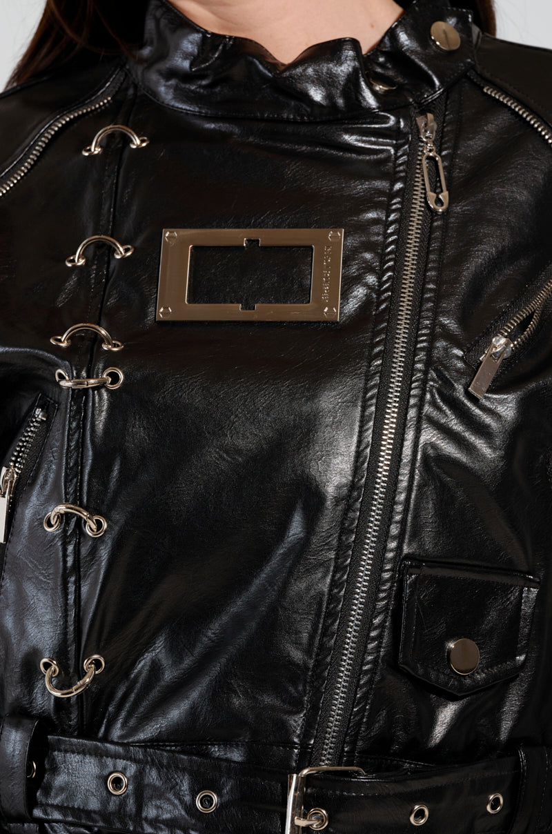 Close-up of the WHY SO SERIOUS METAL TRIM MOTO, a faux leather moto jacket featuring multiple zippers, silver eyelets with laces, and biker-chic metallic hardware detailing. This stylish jacket boasts a high collar and an attached belt at the bottom.