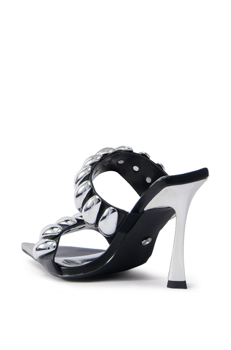 The AZALEA WANG JABARI BLACK STILETTO SANDAL is a black open pointed toe sandal with two straps embellished with large silver metallic beads, a sleek silver heel, and a glossy vegan leather finish, all shown from the rear angle against a white background.