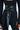 A person dons a black ribbed long-sleeve outfit, accented by the sophisticated ESSENTIAL WRAP AROUND TIE BLACK BELT, elegantly knotted with a long hanging end. Red nail polish adds a striking touch.