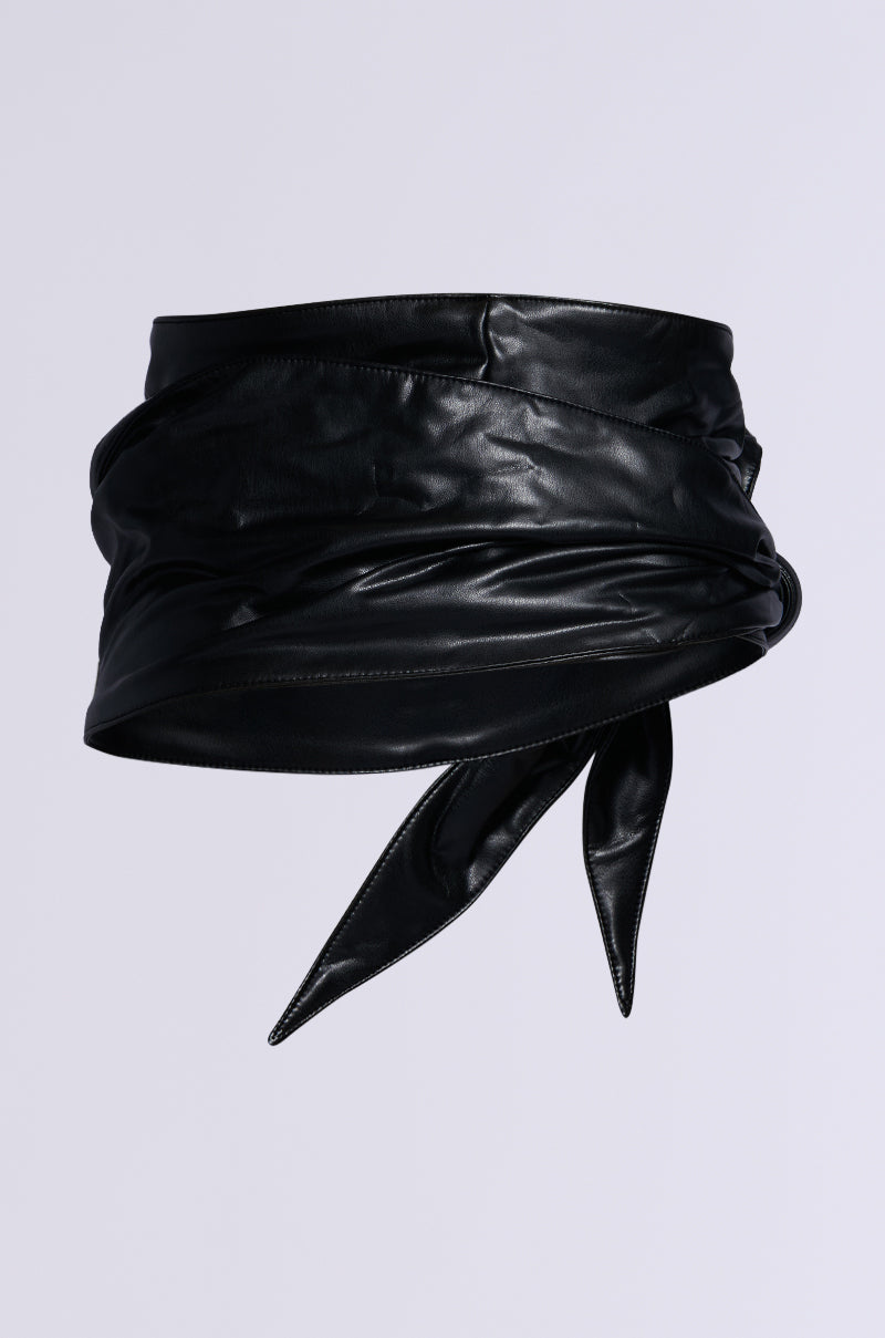 The ESSENTIAL WRAP AROUND TIE BLACK BELT, made from black faux leather with a glossy finish and stylishly knotted pointed ends, adds a sleek touch to any outfit. Its smooth texture and flexibility make it a chic accessory against any plain gray background.