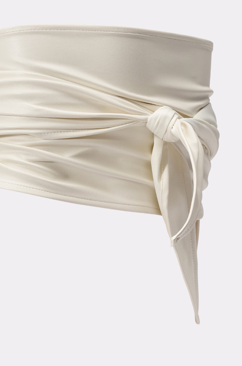 A close-up of the ULTIMATE CINCH PU BELT, an ivory-toned, wide wrap-around belt in smooth fabric, tied at the side—a bold statement accessory. 4