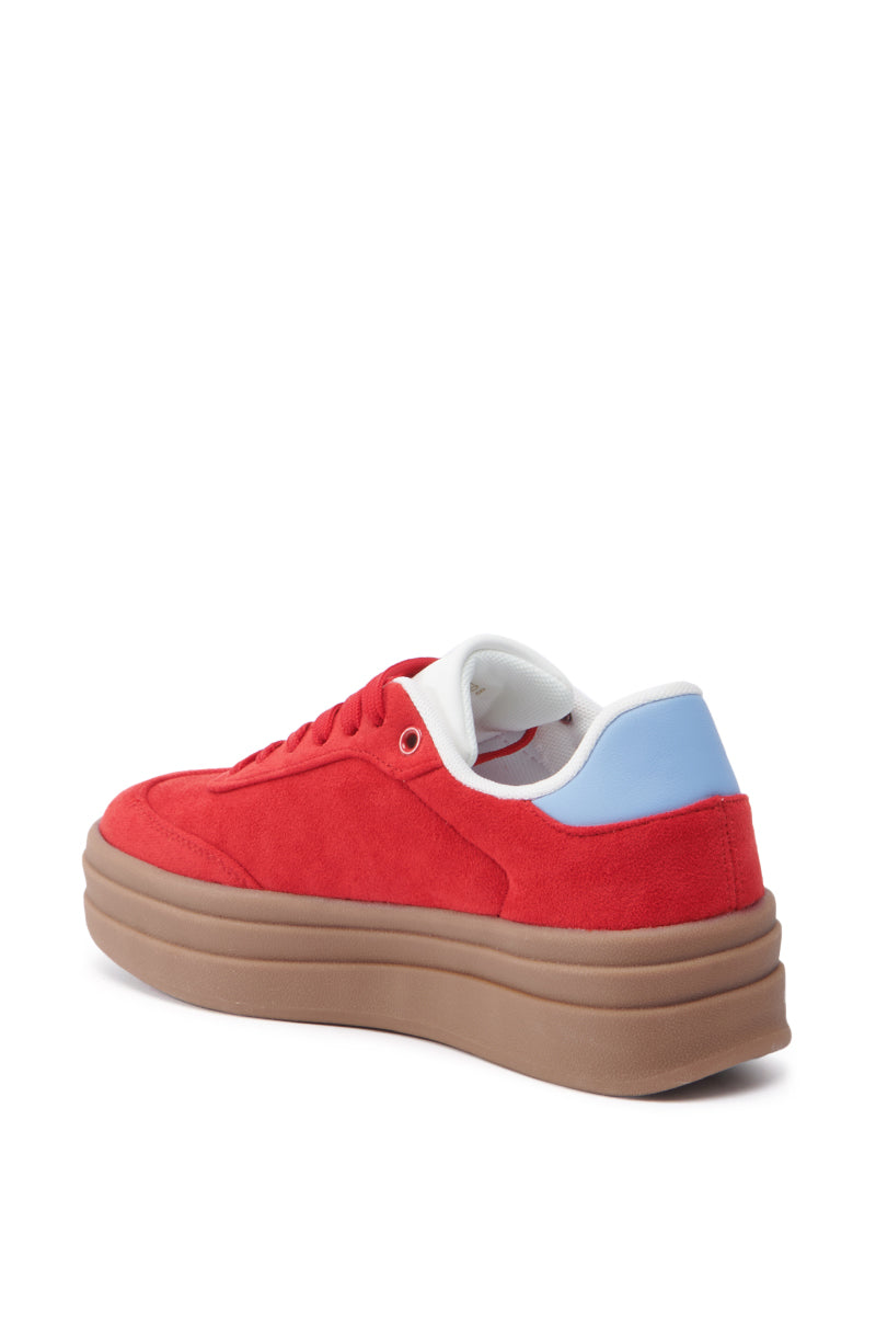 The AZALEA WANG JUMBALAYA RED PLATFORM SNEAKER showcases a vibrant red design with a thick brown sole, light blue heel accent, and white interior lining. The sneaker's almond toe design is highlighted against a plain white background in side and back views.