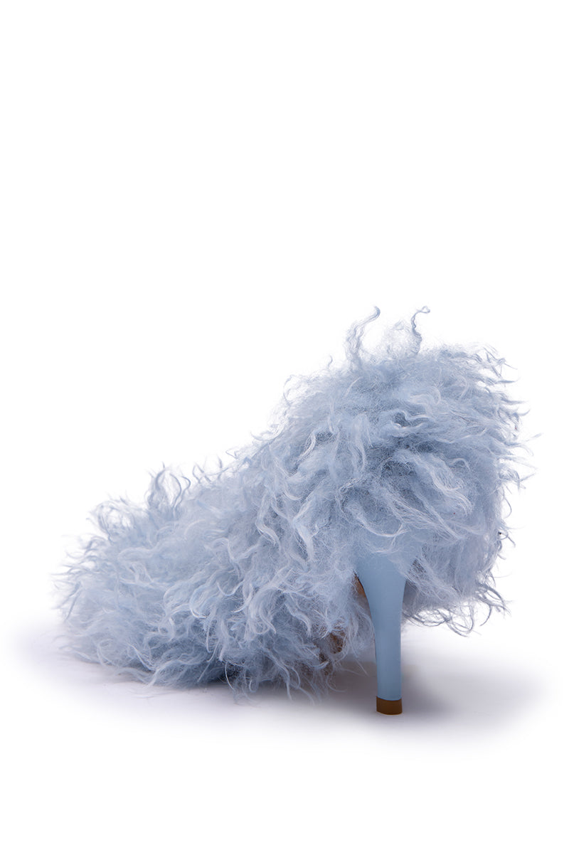 The AZALEA WANG JAMEEKA Baby Blue Curly Fur Pump Stiletto Heel is shown from the back, featuring a high heel covered in fluffy, curly light blue faux fur against a white background.