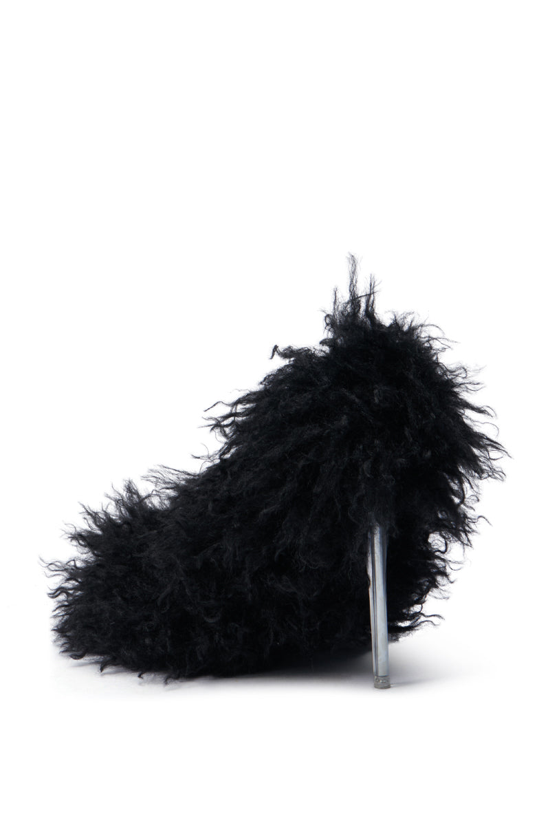 The AZALEA WANG JAMEELA BLACK FUR STILETTO PUMP features a stylish design with its fluffy black faux fur adorning a sleek, transparent heel set against a crisp white backdrop.