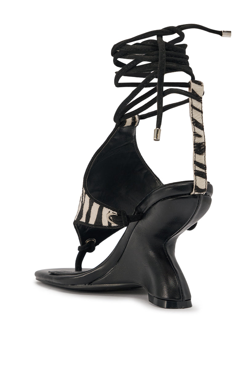 The AKIRA GOLD JANA BLACK ZEBRA CALF HAIR PRINT WEDGE SANDAL features a sculpted heel, bold zebra-print accents, and long black lace-up straps that wrap around the ankle for standout style. 4