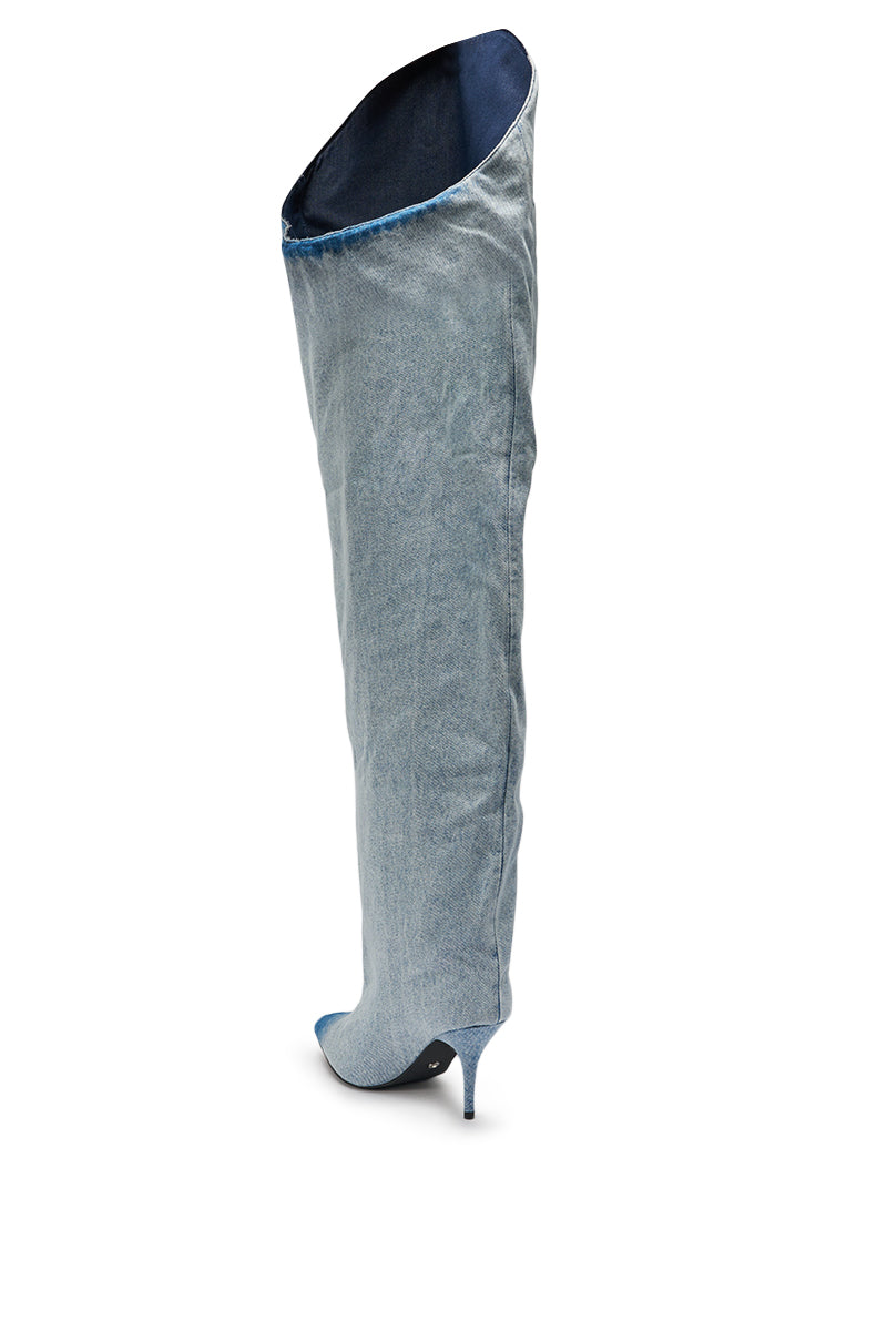 The AKIRA Gold Janelisse Denim Stiletto Boot is a single knee-high, light blue denim boot with a pointed toe, thin high heel, and an exaggerated flared asymmetrical top opening. 5