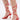 Close-up of a person wearing the AKIRA JANIKA RED HARDWARE STRAPPY SANDAL, featuring red stiletto heels with thin straps wrapping around the ankles and lower legs, tied in bows at the back, against a plain white background.